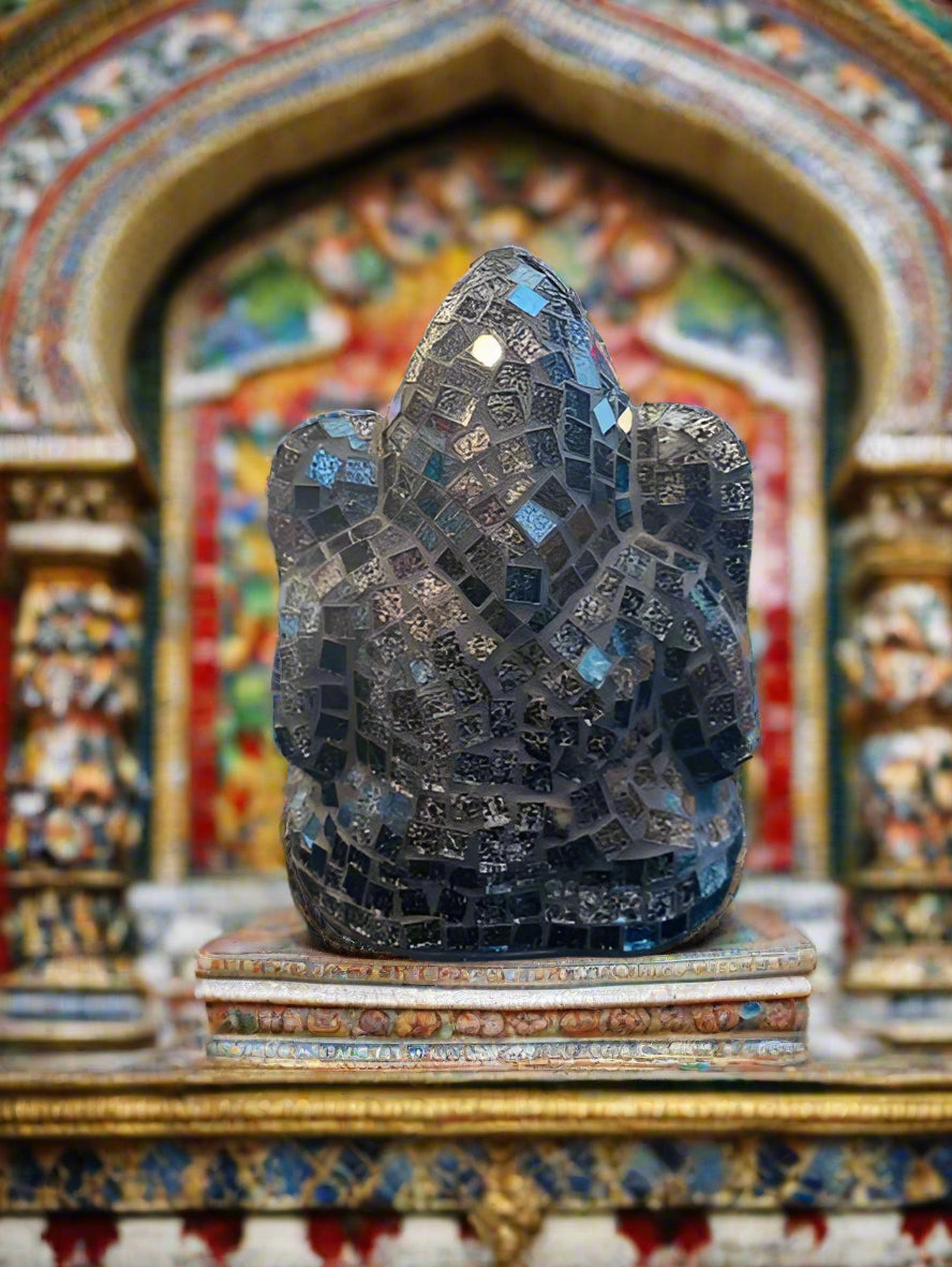Decorative black mosaic sculpture on a reflective surface with a blurred background